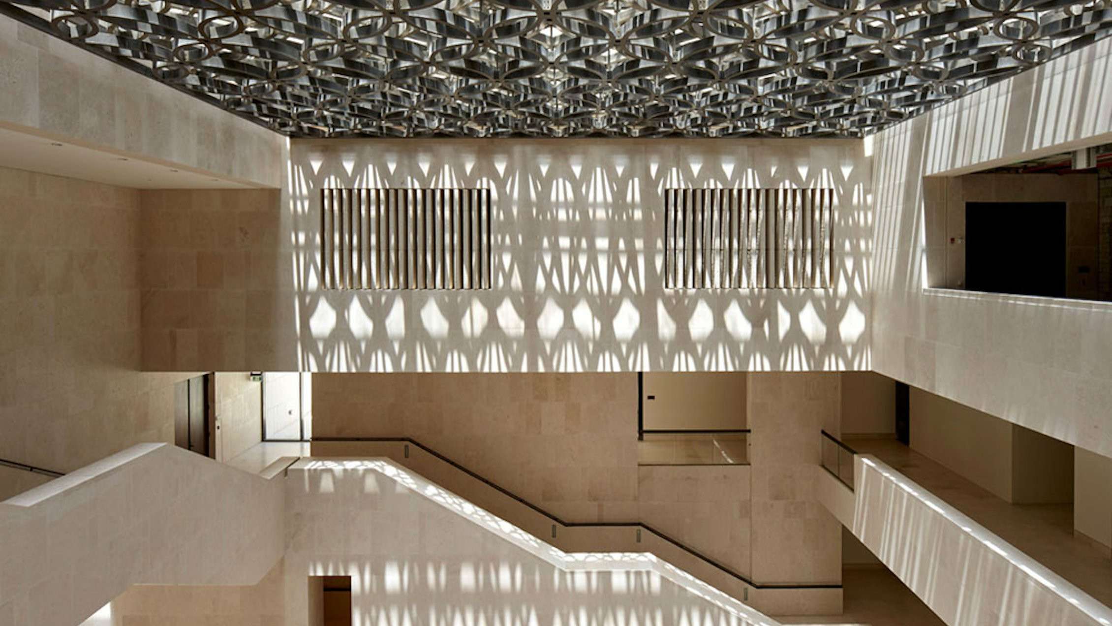 Interior of a modern building featuring light patterns on the wall and a stairway at M7 Msheireb Downtown.