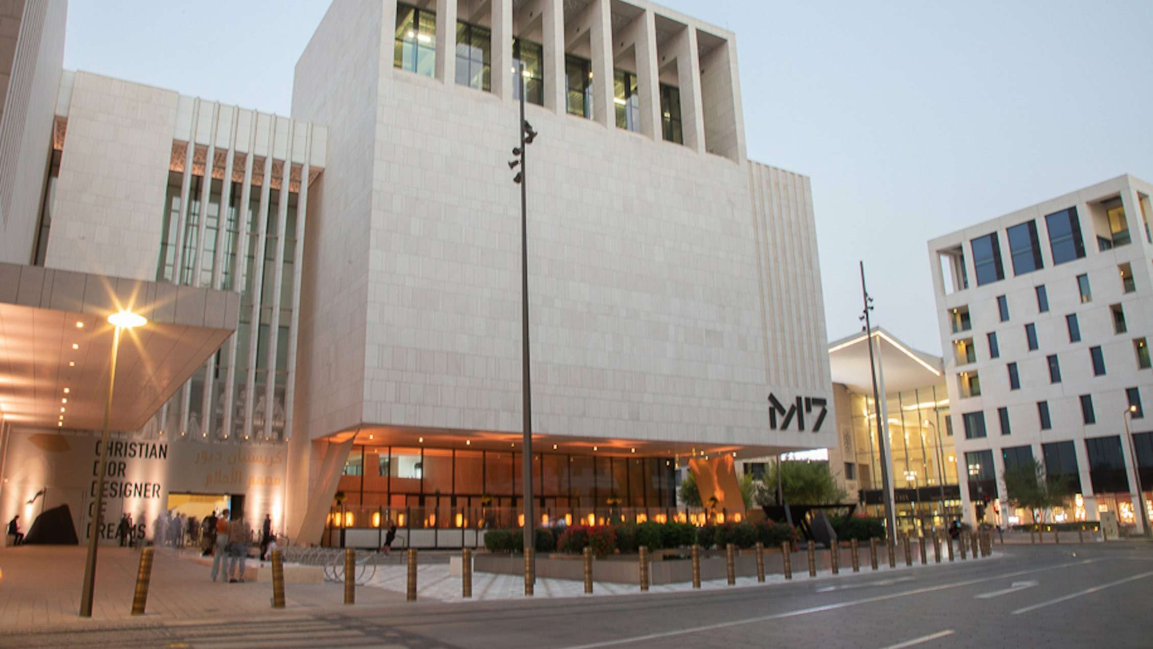 Modern M7 Msheireb Downtown building with bright lights at dusk, featuring M7 on the wall and outdoor seating.
